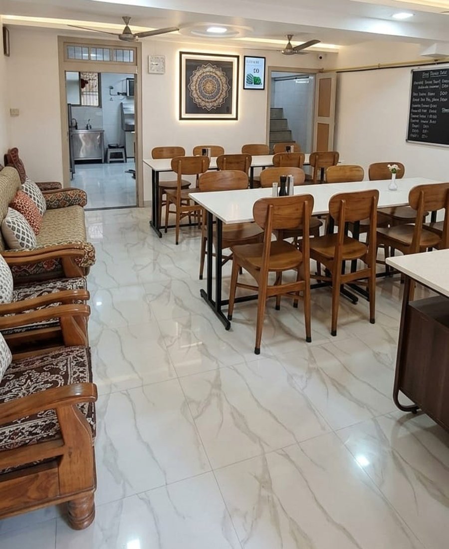 Traditional family dining at Bhagwati Lodge Navsari — warm wooden interiors, Gujarati thali served at table